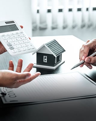 Two people with a calculator and a model house - Big Catch Consulting