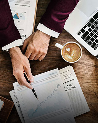 A businessman's hands on a desk, working with a laptop and papers - Big Catch Consulting