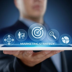A businessman holding a tablet with marketing strategy icons - Big Catch Consulting